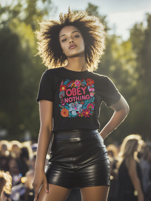 Black activist T-shirt with a floral embroidered-style design and the words “Obey Nothing” in bold, bright lettering.